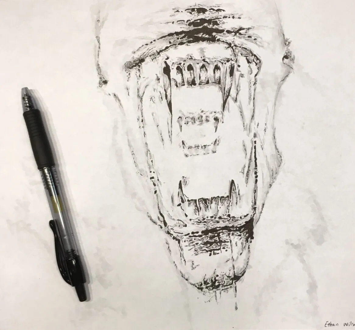 Drawn alien jaws beside a pen