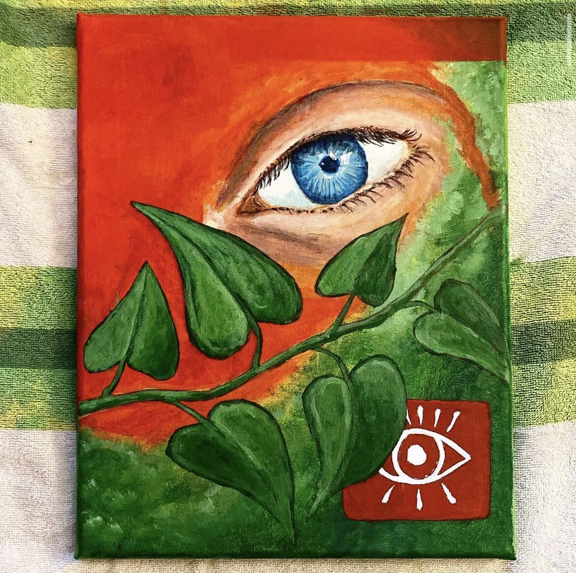 A blue eye behind green leaves