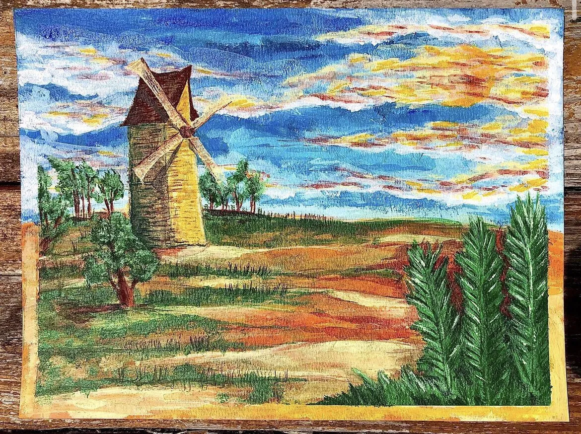 A windmill in a field at sunset